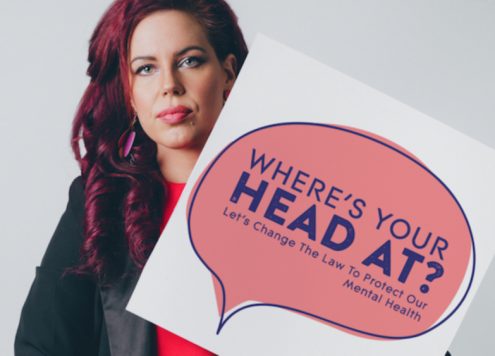 Natasha Devon, author of A Beginner's Guide to Being Mental, holding a sign reading 'Where's your head at'
