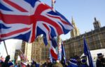 Brexit protesters waving Union Jack flags outside Houses of Parliament.